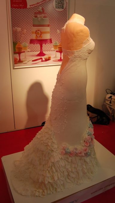Hochzeitstorte in Form eines Brautkleides, dekoriert mit Zuckerguss und Blumen.